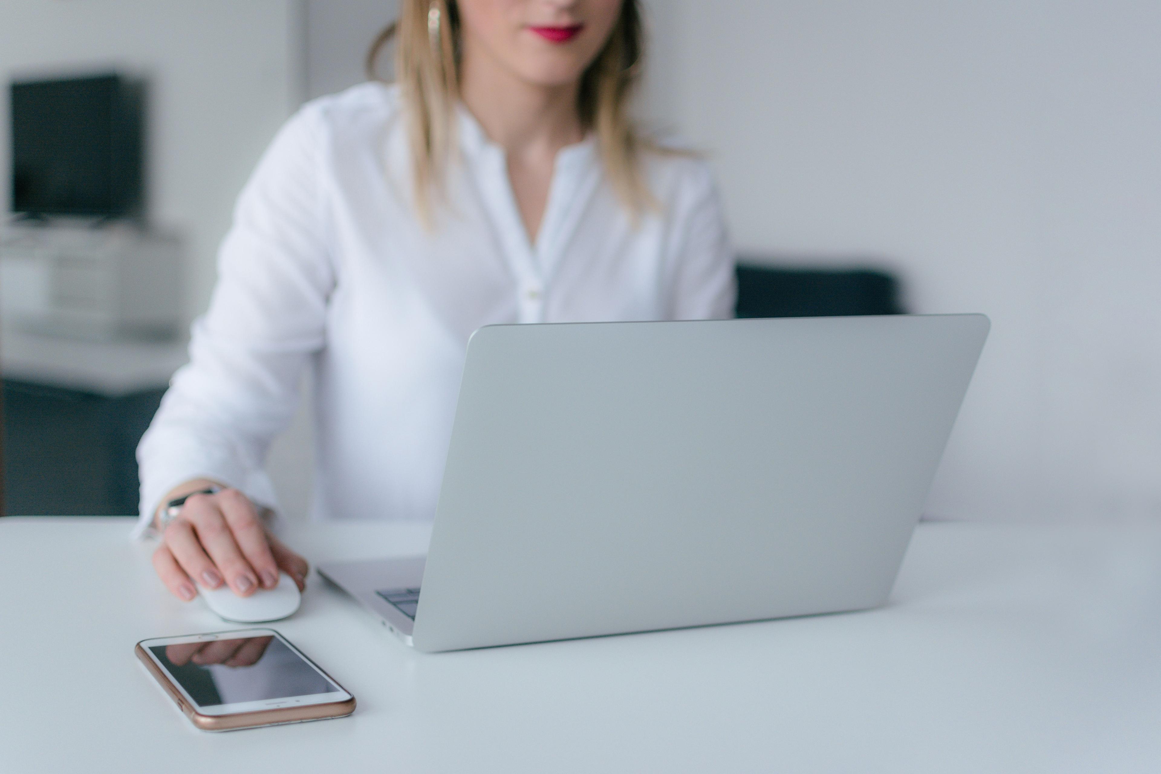 Woman working focused at a desk using a laptop and smartphone
