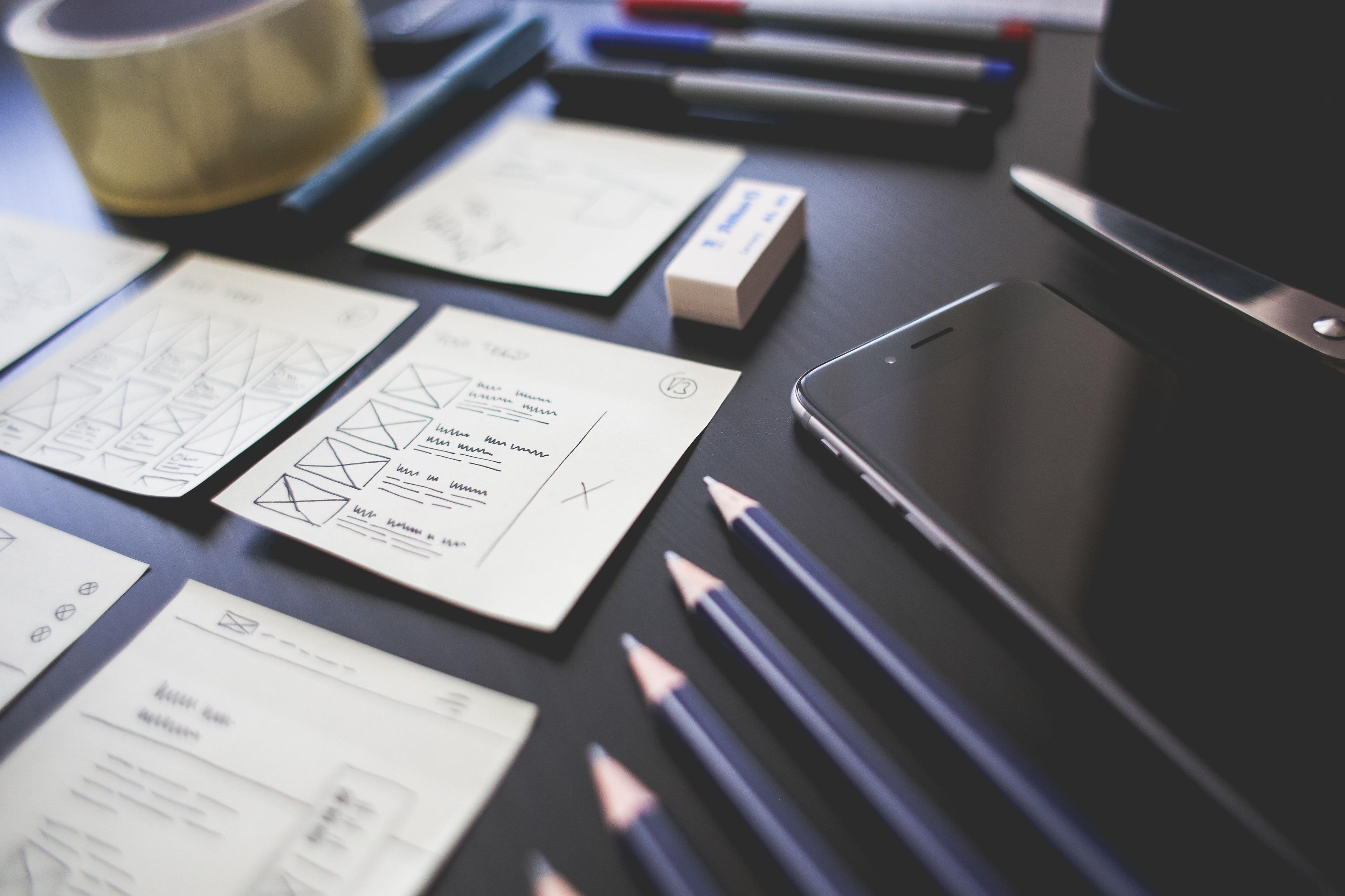 Creative workspace with UI design plans pencils and smartphone on desk