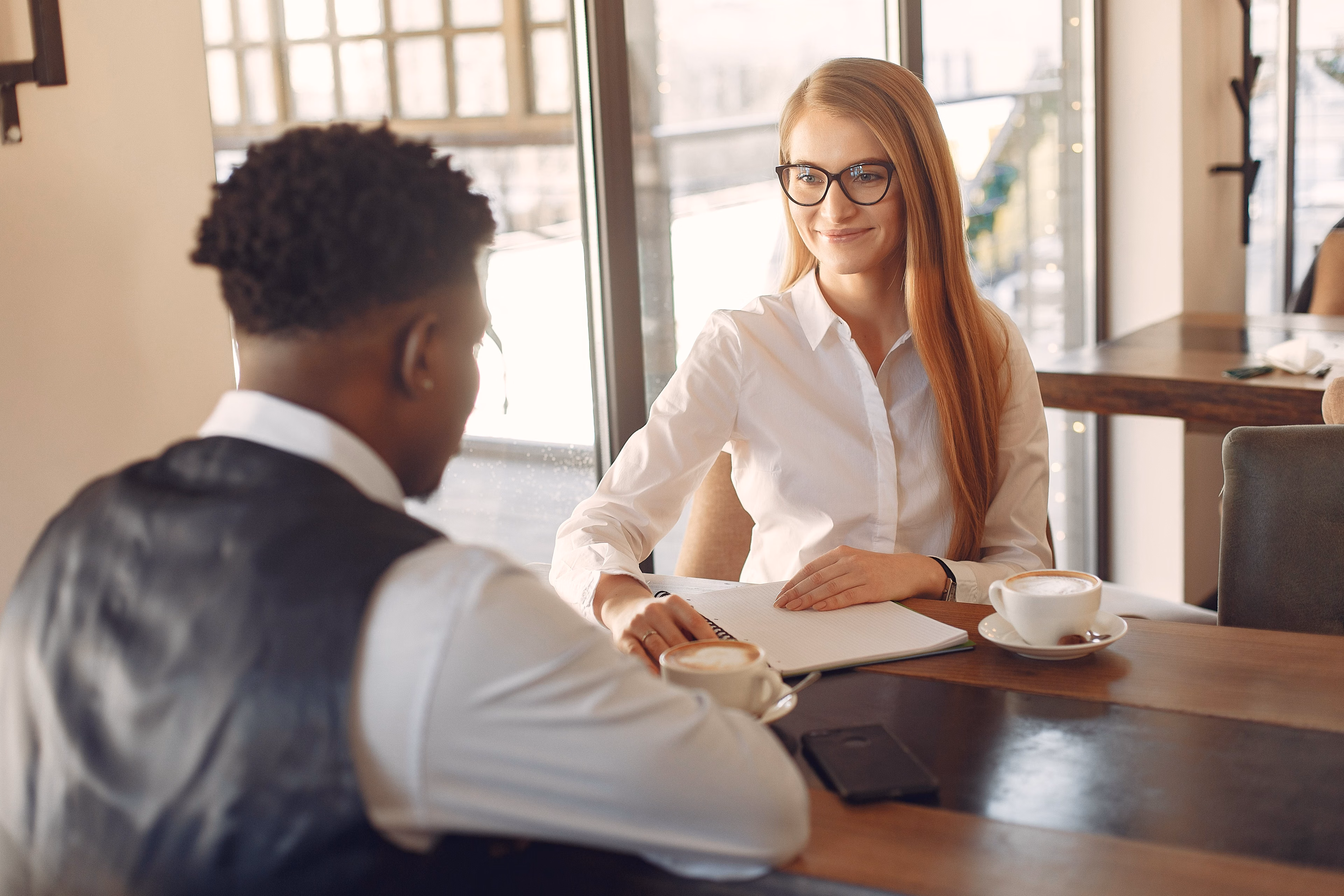 Man being interviewed by a woman in a formal professional setting