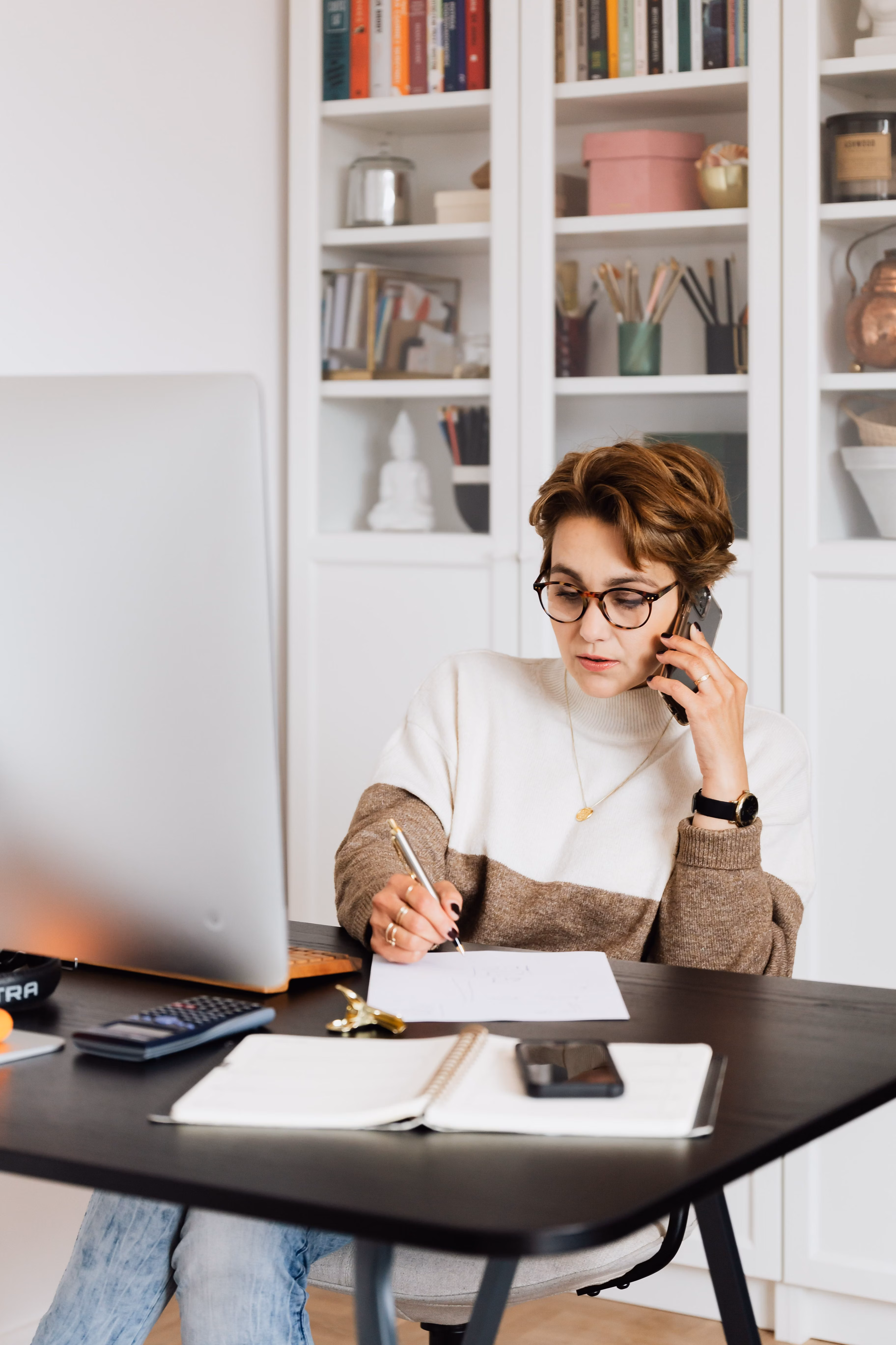 Businesswoman in casual outfit talking on mobile phone in a bright office