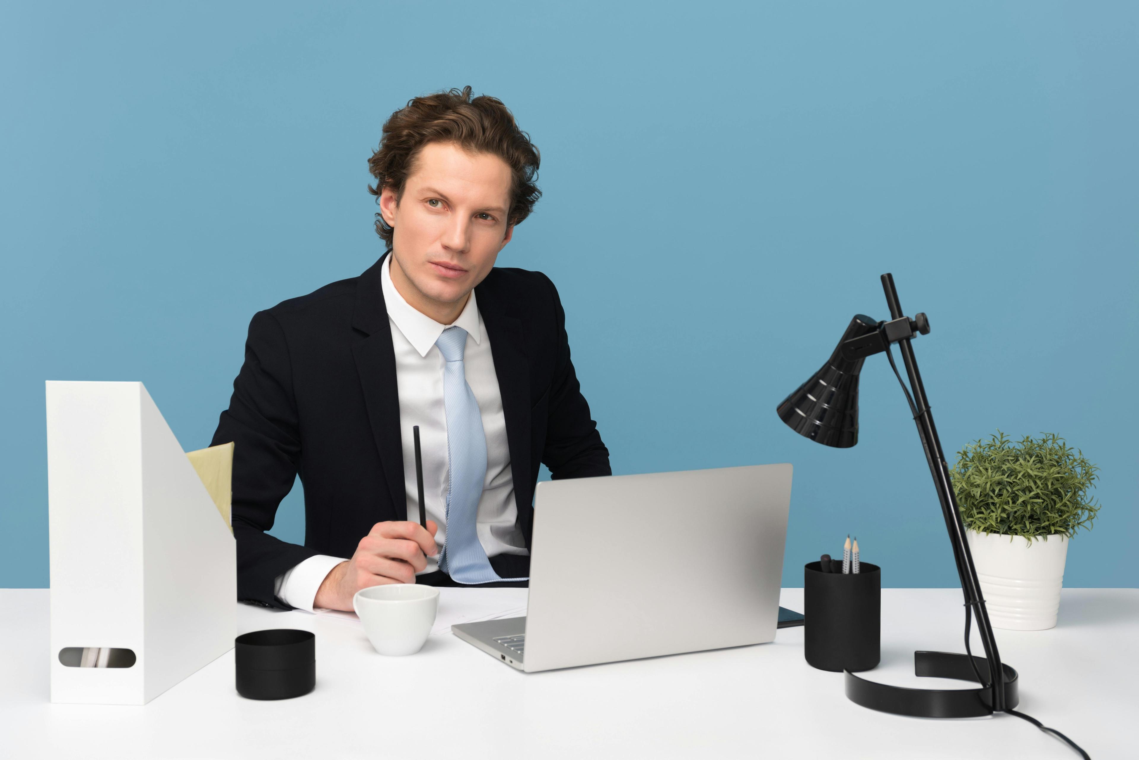 Professional sitting at a clean desk with laptop lamp and plant