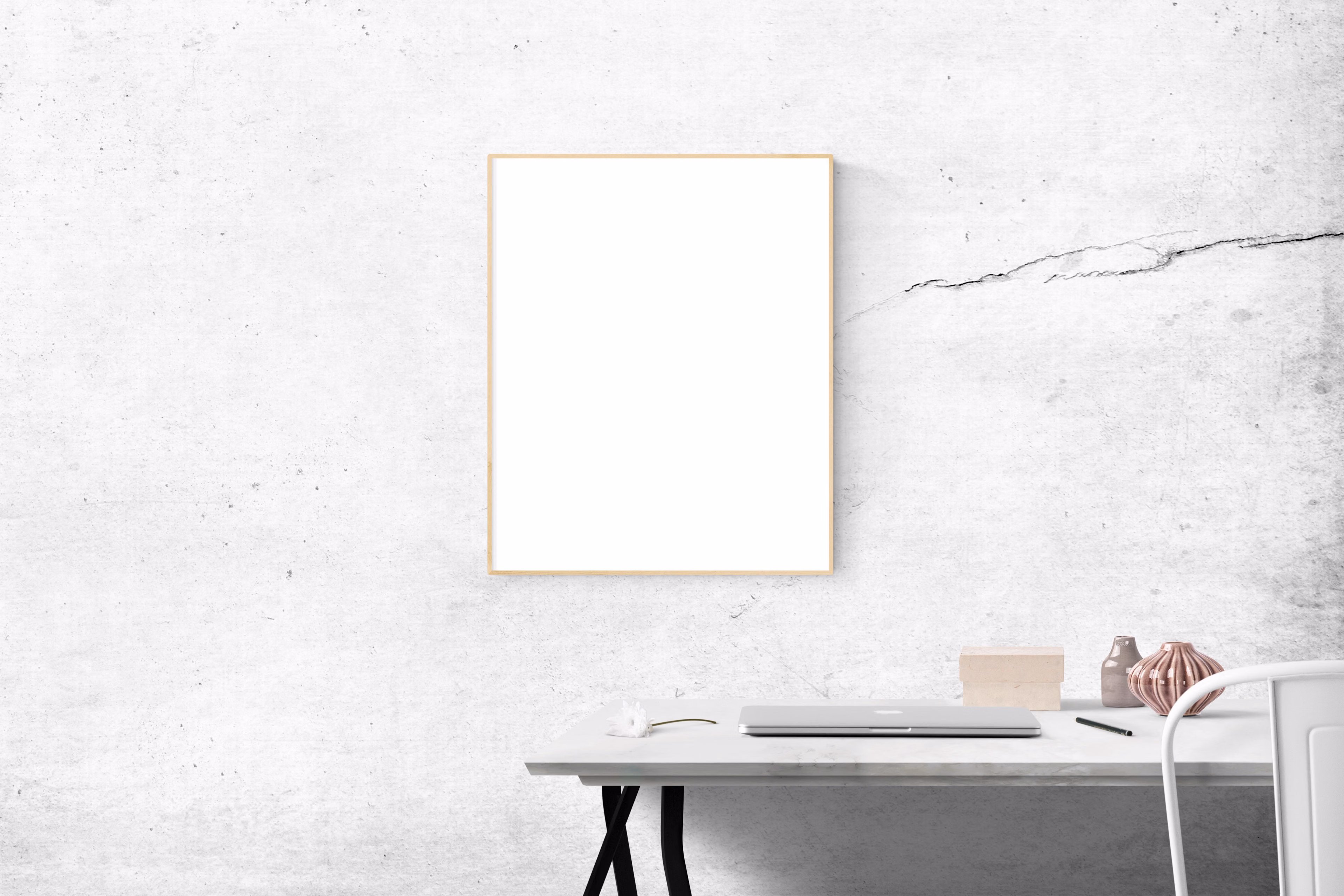 Minimalist workspace with a blank picture frame leaning against a concrete wall
