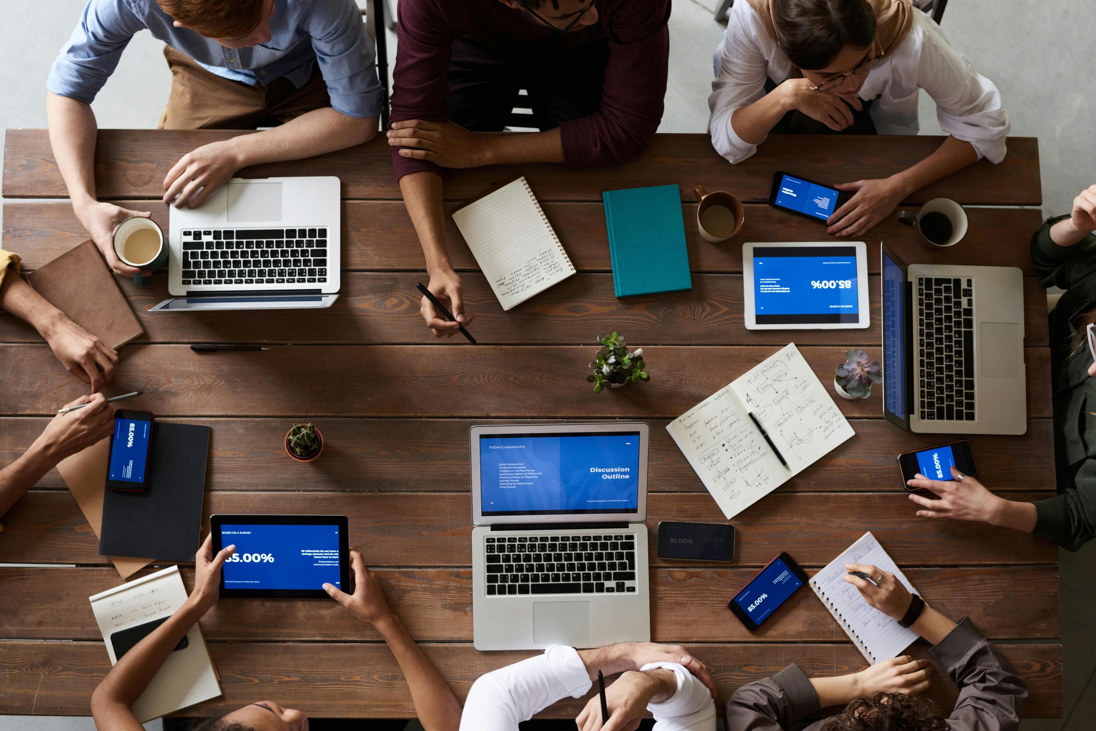 Team collaborating around a table with laptops
