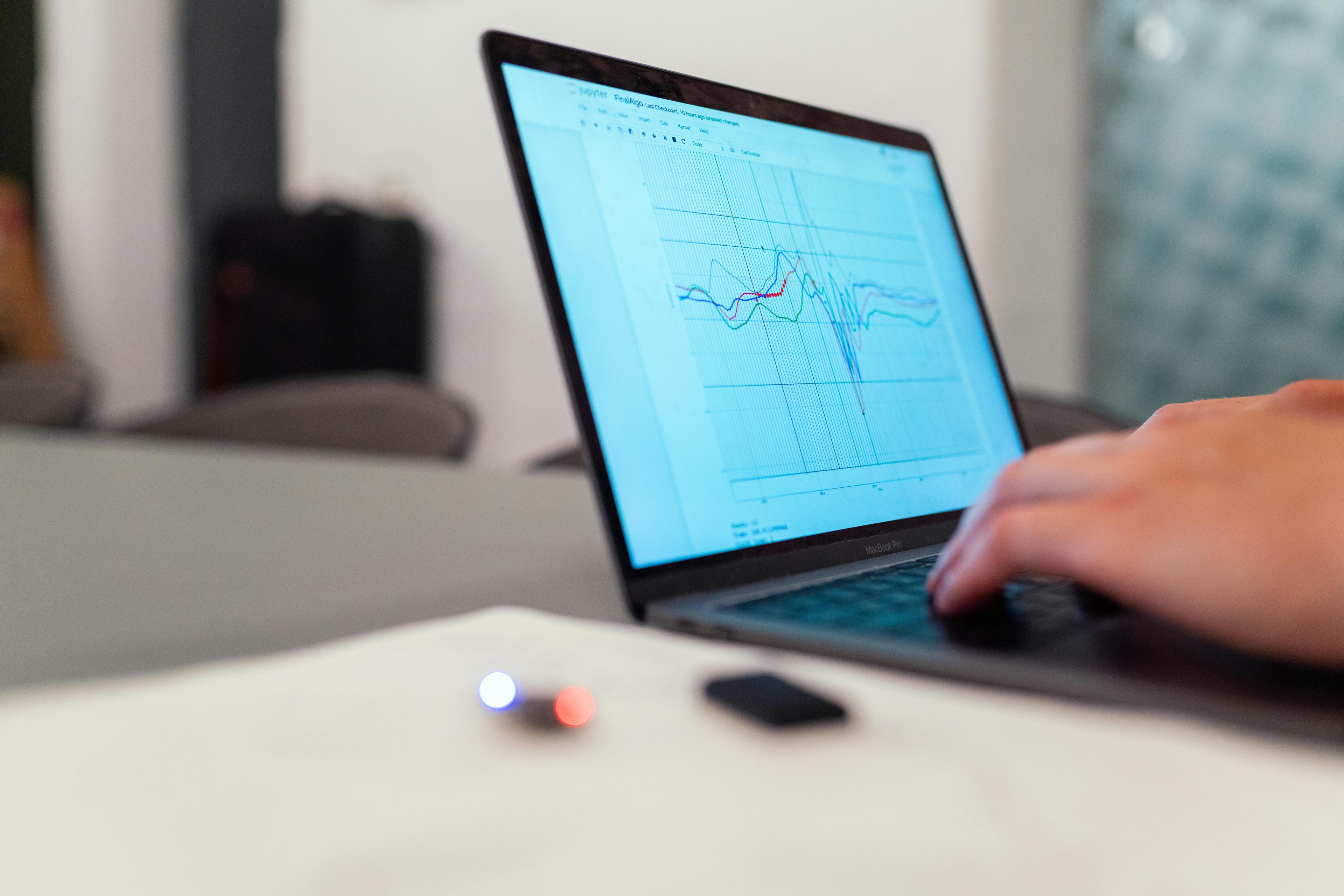 Person analyzing data graph on a laptop screen at their workspace