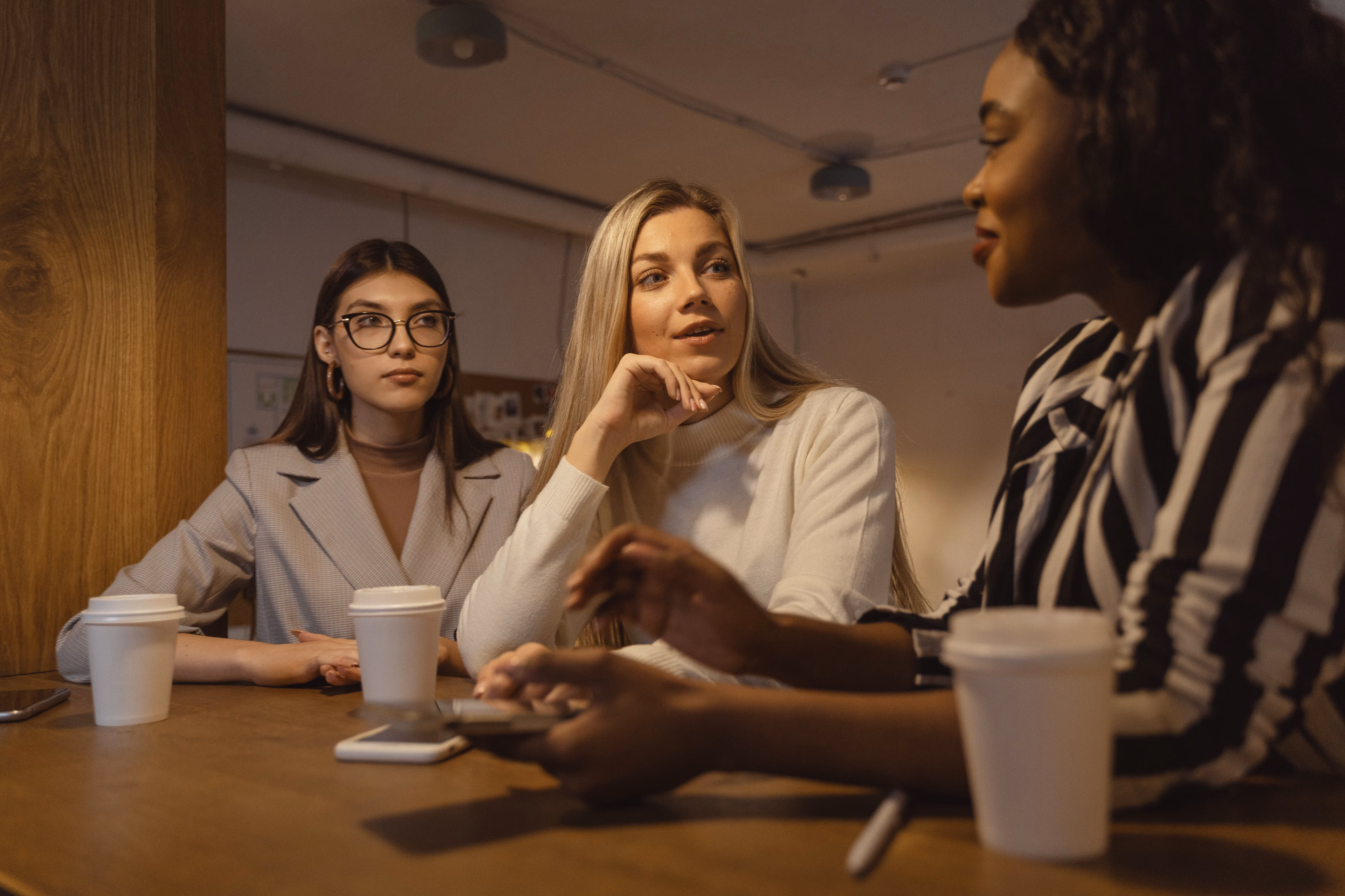 Three women engaged in a business discussion at a coffee shop