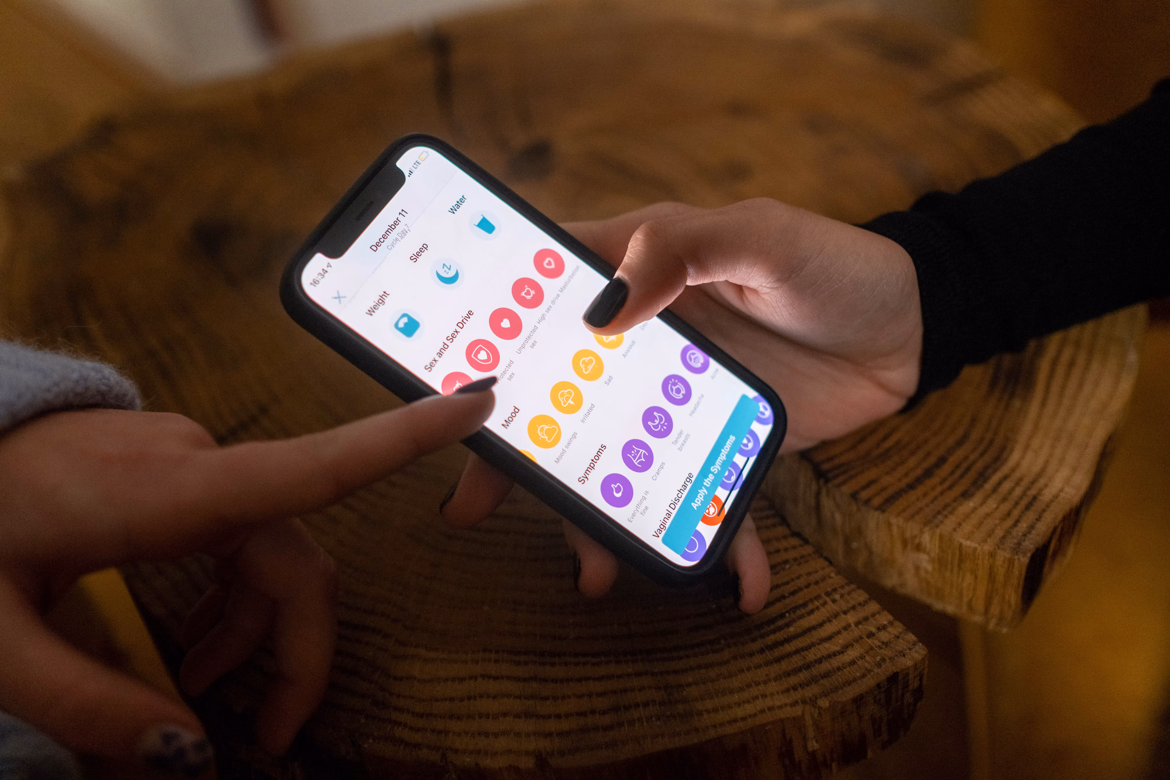 Person holding smartphone with an app open on screen, pointing at display