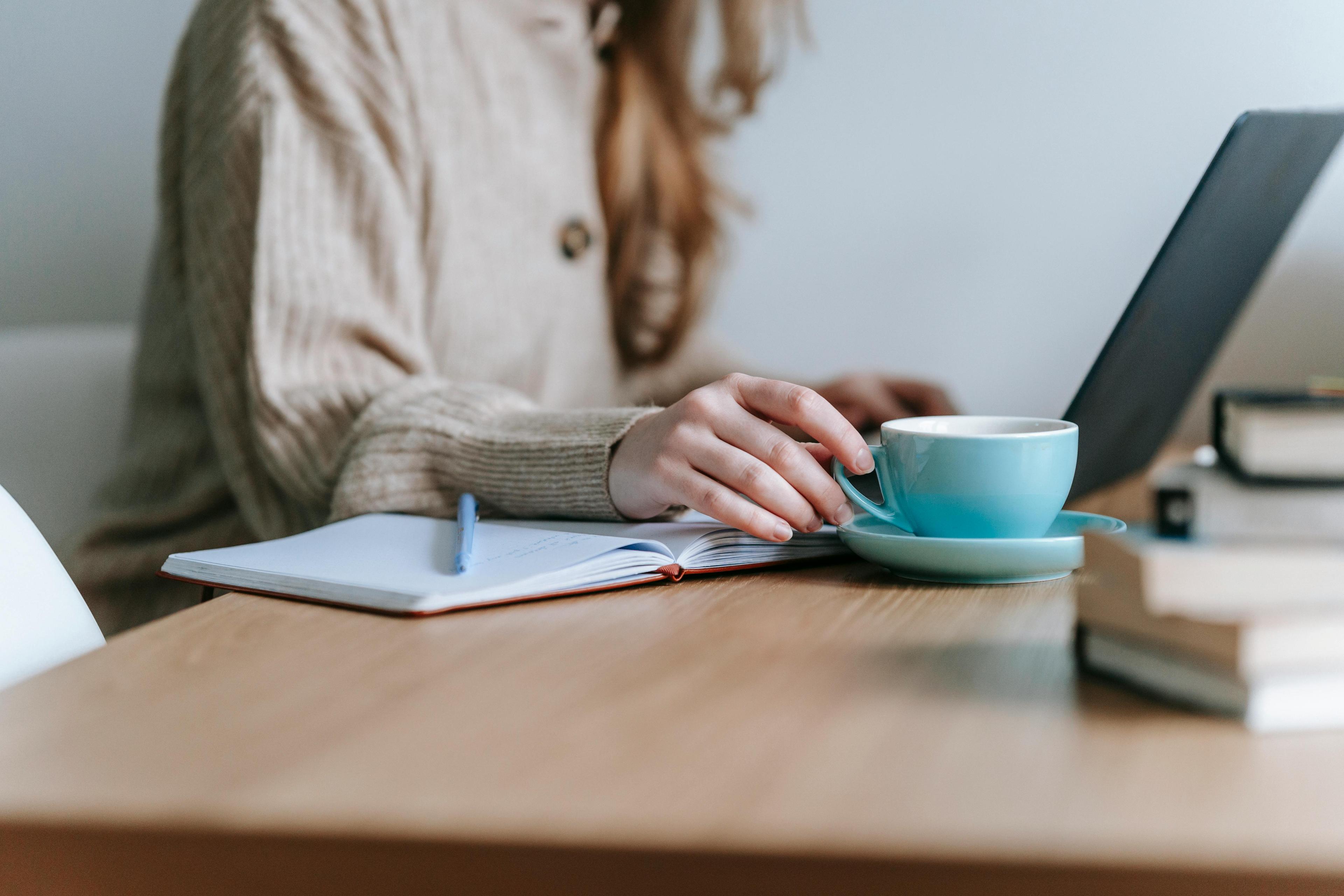 Freelancer creating content at a minimal desk with coffee and notebook