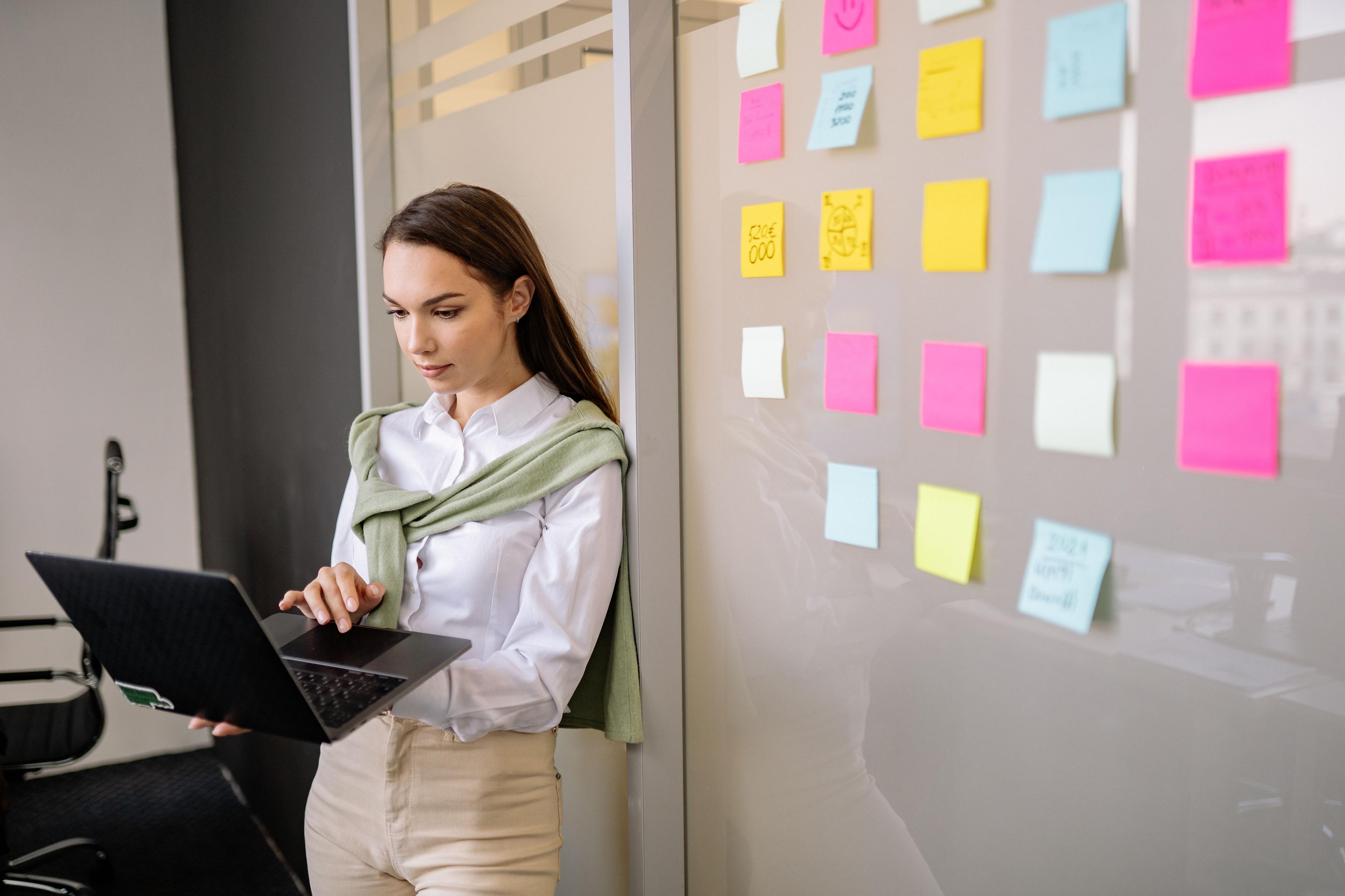 Developer reviewing a prototype on a laptop with sticky notes on wall