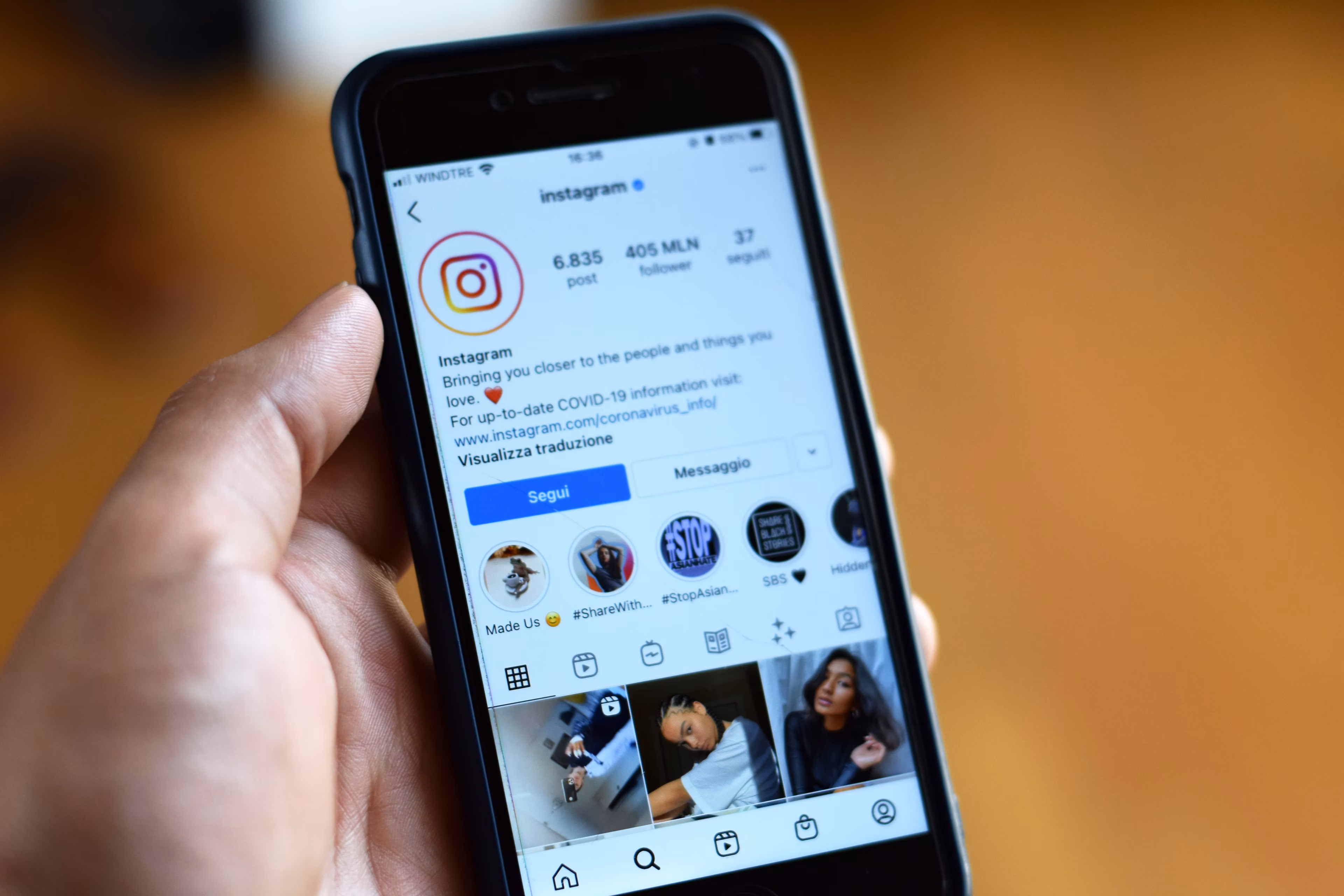 Close-up of a person holding a smartphone displaying an Instagram profile on screen